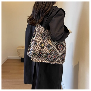 Close-up of ethnic woven tote bag with colorful geometric patterns and wide black strap