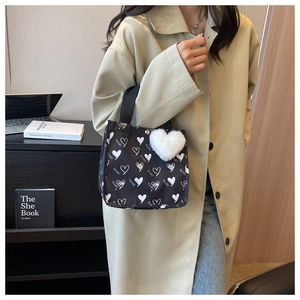 Detail of a black canvas tote with heart patterns and a white plush heart charm
