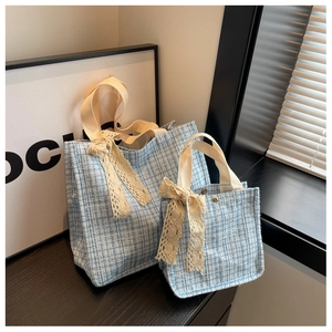Detail of tweed tote bags in two sizes with lace bow accents and beige ribbon handles