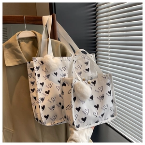 Close-up of heart print canvas tote bag set with plush ball charm and nice! text