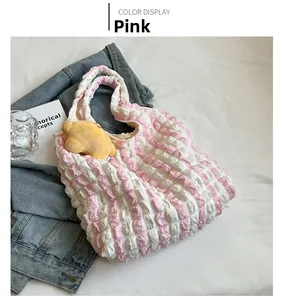 Detailed close-up of pink checkered puff tote bag with star plush charm on soft bed