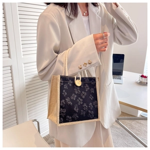 Detailed view of a mini tote bag with black floral embroidery and white rope handle