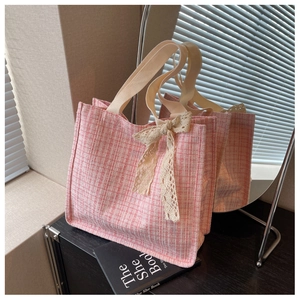Detail of pink tweed tote bag with elegant lace bow and textured fabric handle