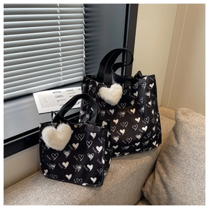 Detail of black canvas tote bag with white heart patterns and plush heart pendant