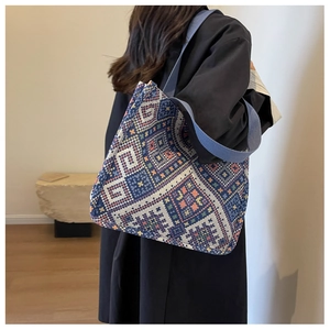 Detail of blue canvas tote bag with orange ethnic geometric patterns and wide strap