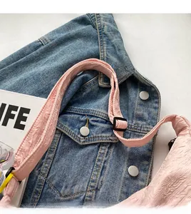 Pink pleated canvas crossbody bag featuring a wide adjustable shoulder strap with buckle
