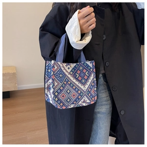 Detail of ethnic geometric woven canvas tote with blue handles and metal snap closure