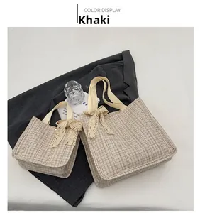 Detail of khaki plaid canvas tote bags with elegant cream lace bow decorations