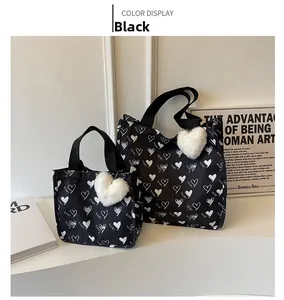 Detail of large black canvas tote bags with heart patterns and plush heart charms