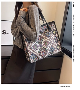 Détail du grand sac cabas en toile tissée géométrique porté à l'épaule par le mannequin