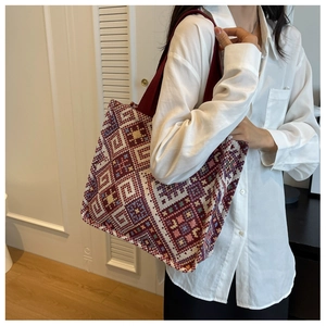 Close-up of geometric jacquard fabric texture and red woven strap on ethnic tote bag