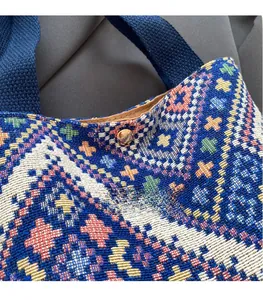 Detail of colorful woven canvas bucket bag showing ethnic pattern and magnetic bronze clasp