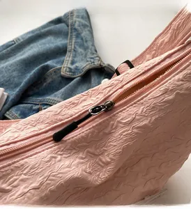 Detail of pink pleated canvas bag featuring a smooth metal zipper and brown inner lining