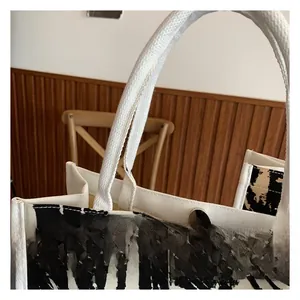 Dettaglio della borsa tote in tela zebrata con chiusura magnetica e manico bianco
