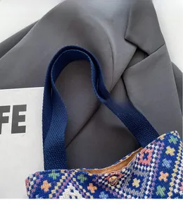 Detail of ethnic jacquard bucket bag showing blue handles and amber magnetic closure