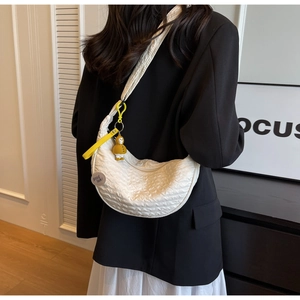 Detail of white pleated nylon crescent bag featuring duck pendant and good luck badge