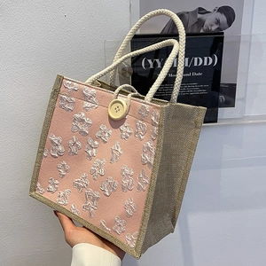 Pink woven fabric tote bag with 3D floral accents and natural jute trim texture