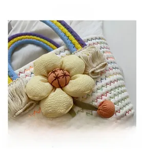 Detail of woven straw bag featuring handmade fabric flower and colorful fiber handles