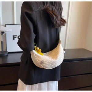 Detailed shot of white hobo bag with embossed fabric texture and a yellow duck charm