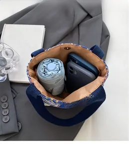 Spacious interior of blue woven bucket bag showing storage for umbrella and phones