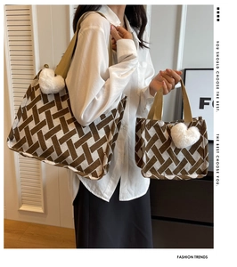Detail of woven brown and white tote bag set with heart charm and shoulder strap