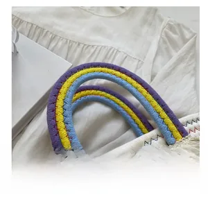 Detail of colorful woven handles with floral charms on a white handmade straw basket bag