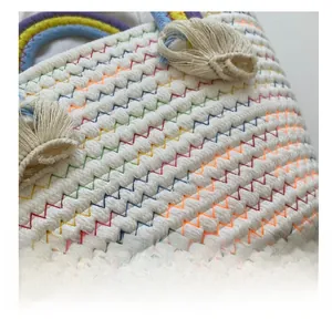 Detailed shot of bohemian woven bag with rainbow stitching and white cotton tassels
