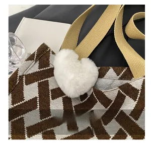Detail of woven tote bag with geometric pattern and soft white heart plush pendant