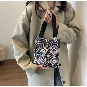 Detail of colorful geometric woven canvas bucket bag with sturdy black ribbon handles
