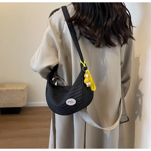 Detail of black crescent canvas bag with 'good luck' patch and yellow duck charm