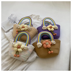 Detail of colorful woven bags with rainbow handles and 3D floral accents on white linen