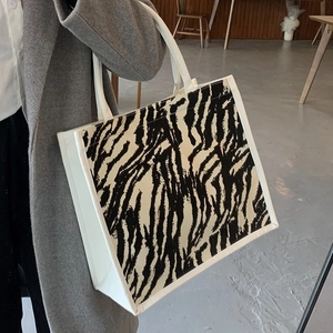 Elegante borsa tote in tela zebrata con manici intrecciati abbinata a un cappotto chic