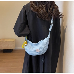 Detail of light blue pleated croissant bag with adjustable strap and duck charm
