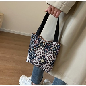 Close-up of geometric knit pattern and gold magnetic clasp on ethnic style bucket bag