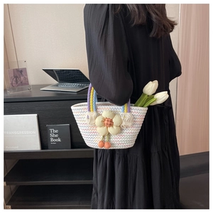 Detail of woven straw basket bag with floral applique and colorful rainbow handle