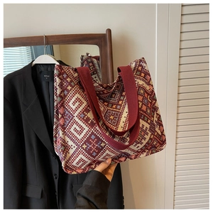 Close-up of ethnic geometric woven tote bag with burgundy straps and boho pattern