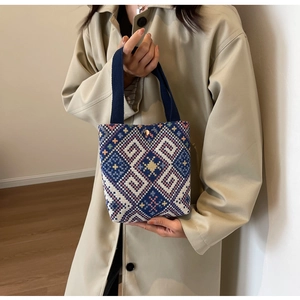 Close-up of ethnic geometric pattern canvas bucket bag with gold snap button and woven handle