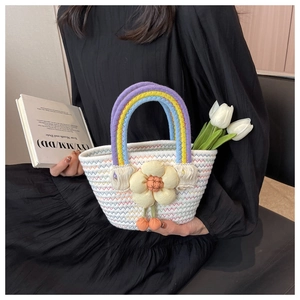 Detail of handmade straw bag with rainbow handles, floral charm and tulip decoration