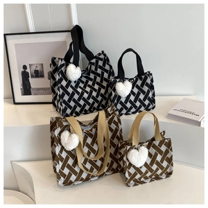 Detail view of woven tote bags in black and brown patterns with plush heart charms