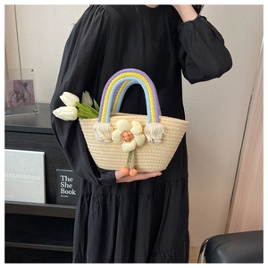 Detail of handmade straw bag featuring rainbow woven handles and 3D floral decoration
