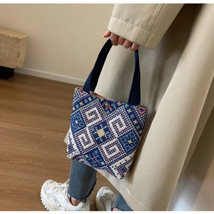 Macro detail of ethnic woven mini tote bag featuring navy blue geometric pattern fabric