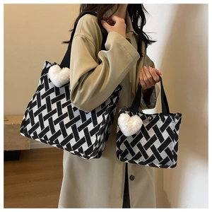 Detail of black and white woven tote set with plush heart charm and matching pouch