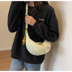 Detail of creamy white crossbody dumpling bag in textured bubble fabric with yellow strap