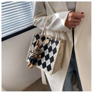 Close-up of checkered linen tote with rope handle and cute rabbit doll pendant decoration