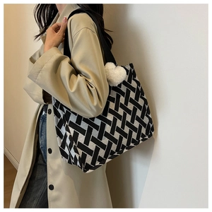Detail of large canvas tote bag with black and white geometric weave and heart charm