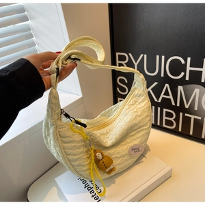 Detailed view of cream hobo bag with pleated texture and cute yellow charm accessory