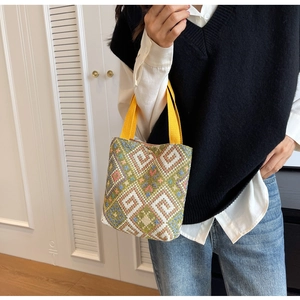 Detail of multi-colored geometric woven handbag with vibrant yellow canvas handle