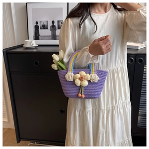 Detail of lavender woven handbag with 3D floral accent and colorful braided handle
