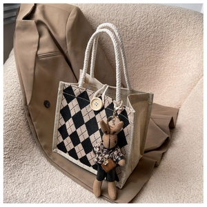 Close-up of linen tote bag with lattice pattern, thick rope handle, and cute bunny charm