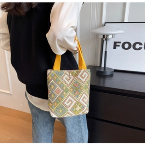 Detail of vintage geometric woven tote bag with vibrant yellow handles and magnetic closure